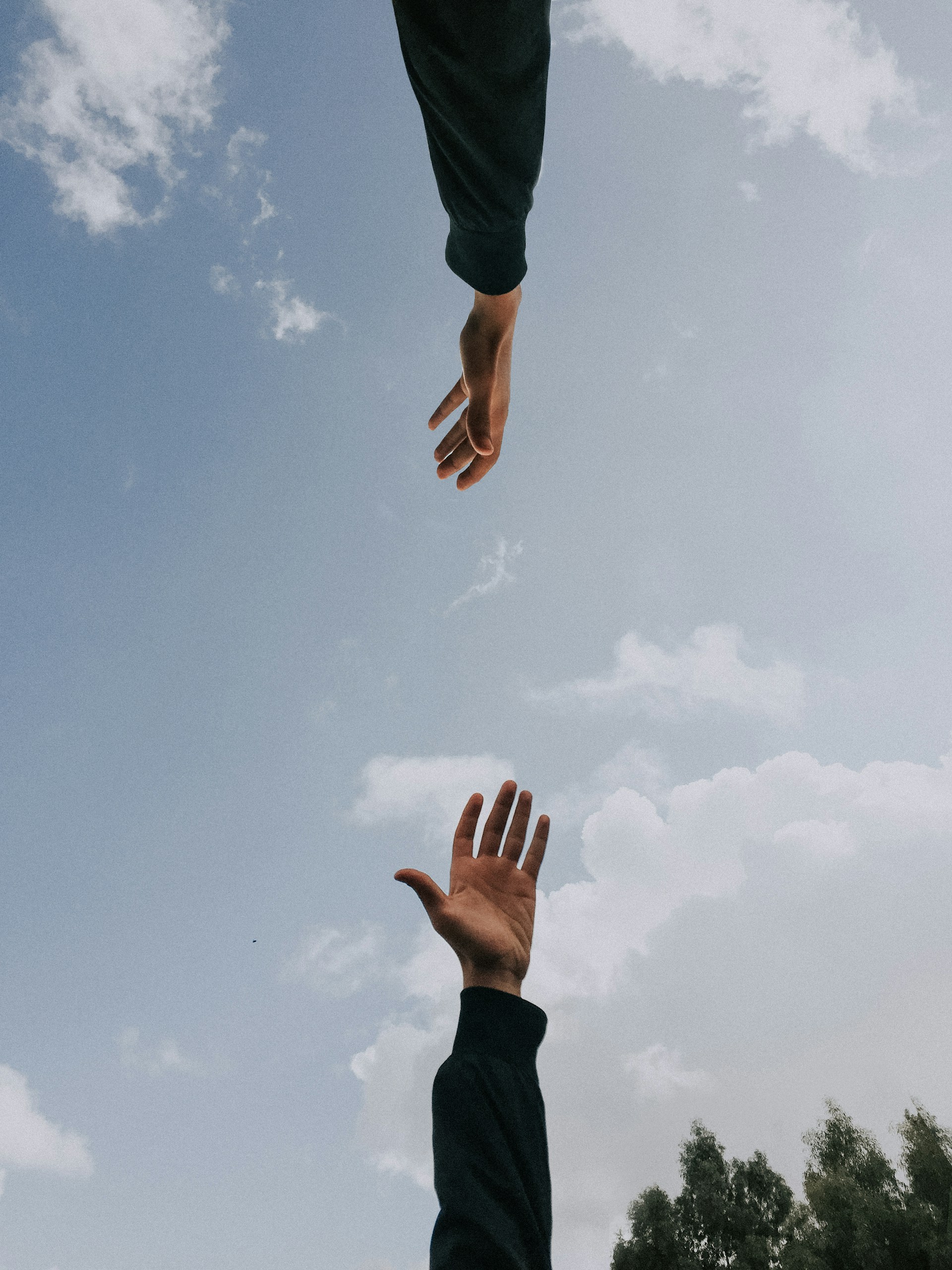 Duas m&atilde;os que se aproximam sob o c&eacute;u, representando acolhimento e apoio